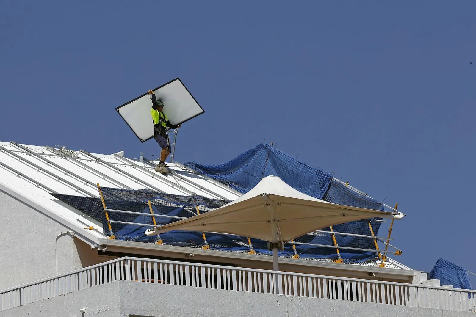 An installer carrying a solar panel across a roof