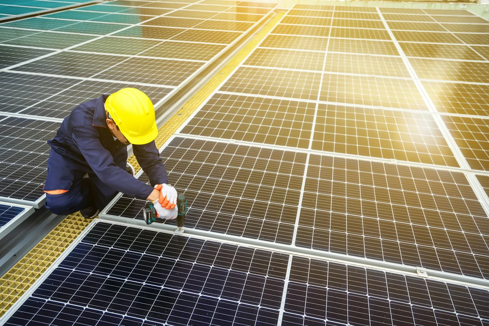 An installer in a hard hat working on a rooftop solar array